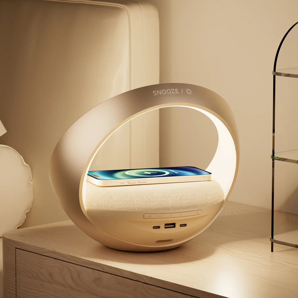 Le Doux Reveils Réveil Connecté 4-en-1 est posé sur une table de nuit en bois. Il offre un haut-parleur Bluetooth, une recharge sans fil, une lampe RVB à lumière chaude, un réveil et des commandes tactiles, le tout dans un design épuré et moderne.
