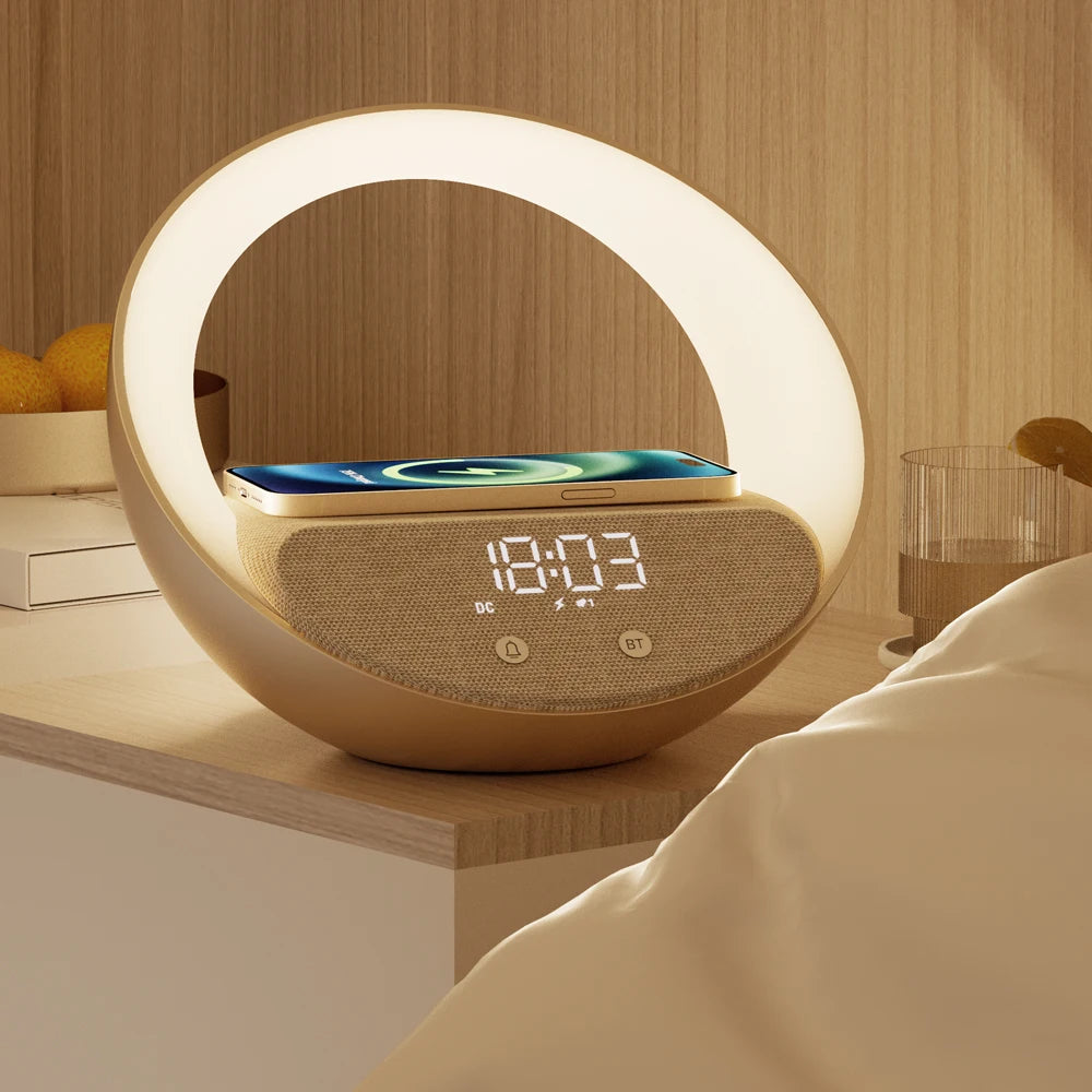 A Doux Reveils Réveil Connecté 4-en-1 avec enceinte Bluetooth, chargeur sans fil, lampe RGB et alarme repose sur la table de nuit à côté du lit, avec des oranges et un verre d'eau en arrière-plan.