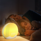 Réveil LED Aube Colorée Double Face illuminant une chambre avec mère et enfant endormies.