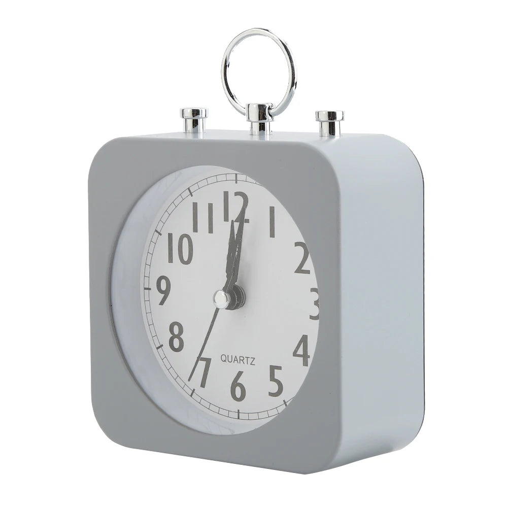 Réveil carré gris au design moderne vu de côté, avec cadran blanc et anneau chromé.