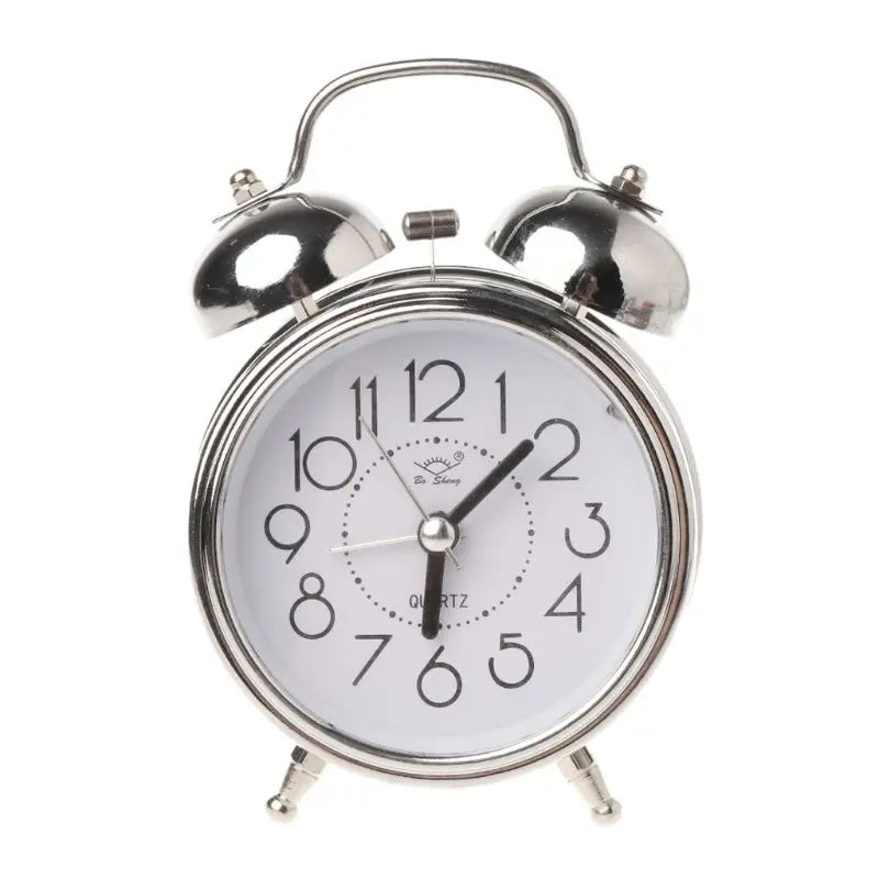 Réveil vintage argenté à double cloche, cadran blanc et chiffres noirs sur fond clair.