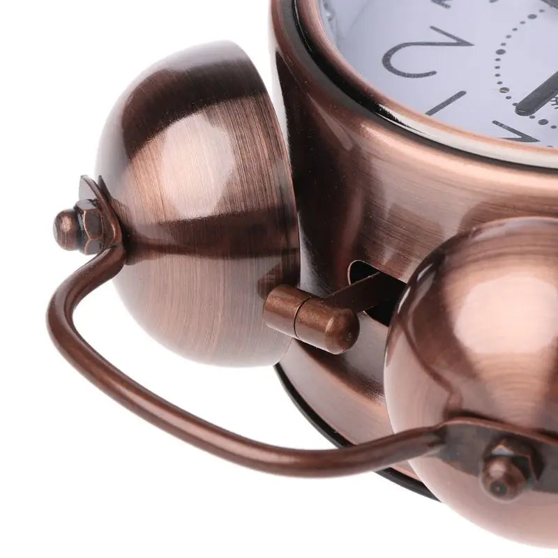 Détail du haut du réveil vintage métallique montrant les deux cloches et la poignée.