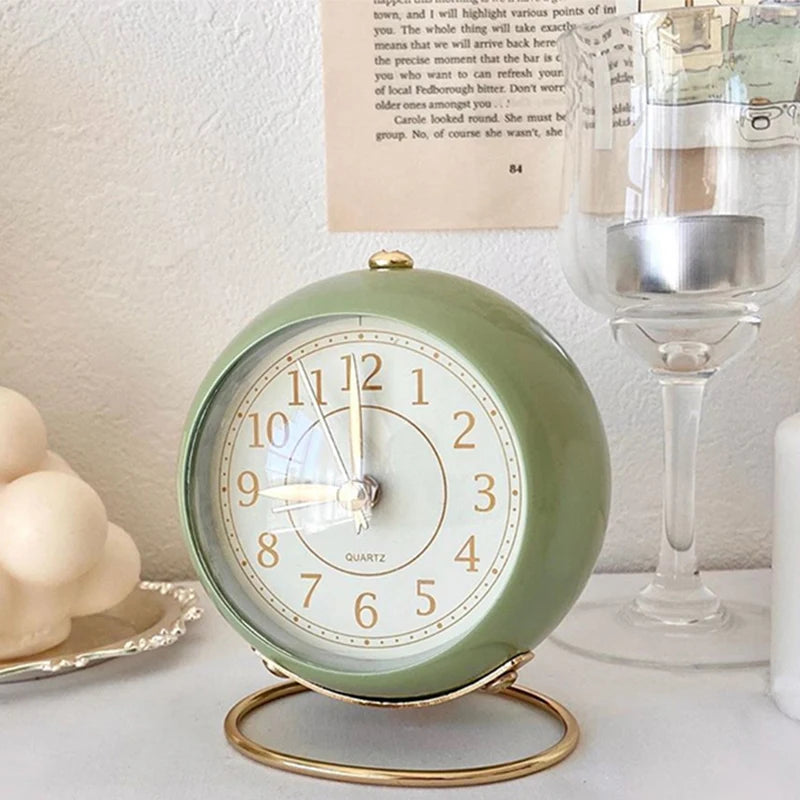 Réveil Vintage Silencieux Rond vert pastel sur table avec bougie et verre décoratif, ambiance douce et élégante.