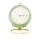  Réveil Vintage Silencieux Rond Vert crème sur fond uni, mettant en valeur son support doré raffiné.