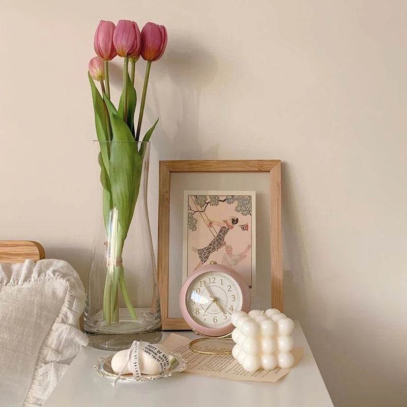  Réveil Vintage Silencieux Rond rose pastel sur table de chevet avec tulipes et décoration minimaliste.