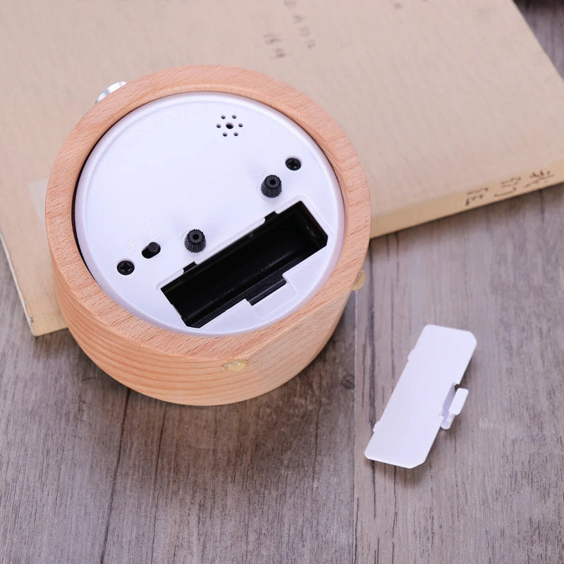 Arrière du réveil en bois avec couvercle du compartiment à piles retiré et posé à côté.